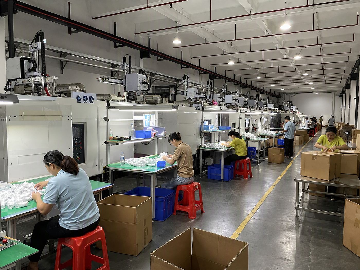 Compression moulding hall with rows of presses and operators trimming and packing parts